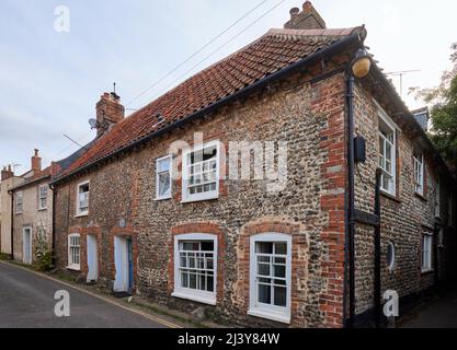 Scena stradale con pareti in pietra fiint di stile locale Blakeney, un piccolo villaggio costiero nella costa settentrionale di Norfolk, East Anglia, Inghilterra Foto Stock