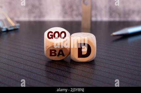 Simbolo buono o cattivo. La mano dell'uomo d'affari trasforma un cubo e cambia la parola 'cattivo' in 'buono'. Bel tavolo giallo, sfondo bianco, spazio copia. Affari Foto Stock