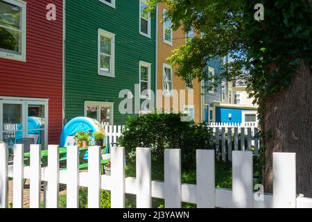 Una vista verso l'alto di un esterno di più case di legno unite colorate con finestre appese doppie. Ci sono case rosse, verdi, gialle e blu. Foto Stock