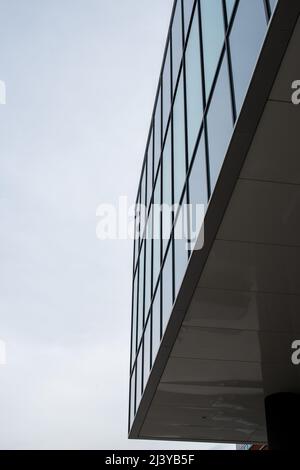 La parete esterna di un edificio contemporaneo di stile commerciale con pannelli compositi in alluminio e finestre in vetro. E' un edificio futuristico. Foto Stock