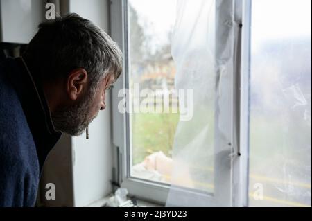 Borodyanka, Kiev, Ucraina. 10th Apr 2022. Un uomo guardò fuori da una finestra rotta. Residenti, volontari e soccorritori svolgono lavori di recupero e pulizia nella città di Borodyanka, a nord-ovest di Kyiv, gravemente danneggiata durante gli attacchi russi. (Credit Image: © Valeria Ferraro/ZUMA Press Wire) Credit: ZUMA Press, Inc./Alamy Live News Foto Stock