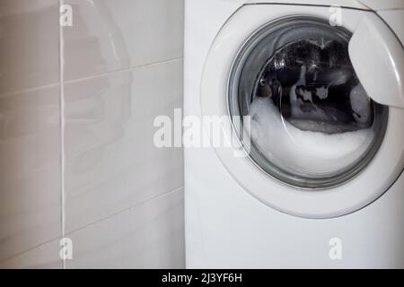 la lavanderia viene lavata in una lavatrice. Bolla in schiuma detergente Foto Stock