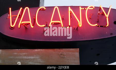 Insegna rossa al neon Vacancy che si illuminano, motel o hotel su strada in California USA. Testo illuminato sull'alloggio durante il viaggio su strada. Turismo o viaggiare in America. Foto Stock