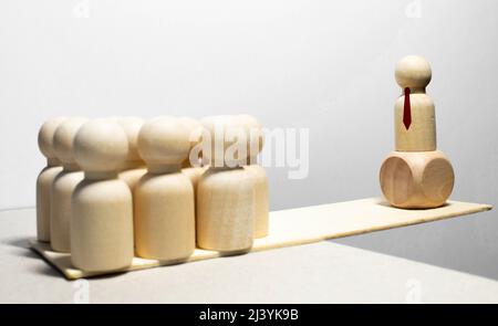 Due gruppi di figure in legno di persone e di un segno di spunta verde sulla bilancia. scontro di potere e opposizioni. concetto di sostegno politico, vot Foto Stock