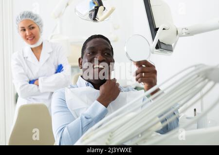 Allegro afroamericano dopo la procedura dentale in ufficio dentista Foto Stock