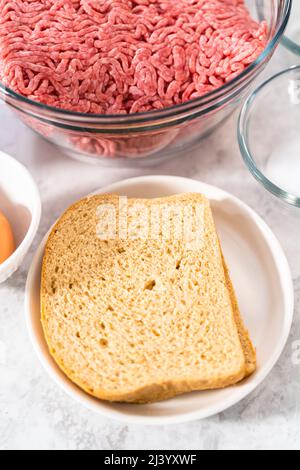 Ingredienti misurati in recipienti di miscelazione in vetro per preparare il polpettone. Foto Stock