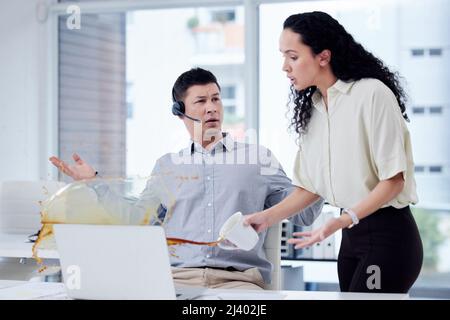 Quanto può essere maldestro. Shot di una donna d'affari che spillava una tazza di caffè sulla scrivania di un collega in un call center. Foto Stock
