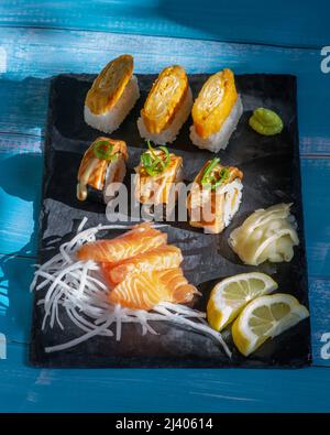 Sushi assortiti e piatto di sashimi. Involtini di sushi di salmone, sashimi di salmone, Wasabi, zenzero, limone. Foto Stock