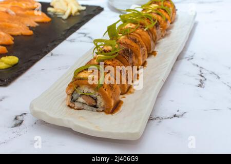 Involtini di sushi di salmone su un tavolo di marmo bianco. L'immagine può essere utilizzata in modo editoriale o commerciale. Foto Stock