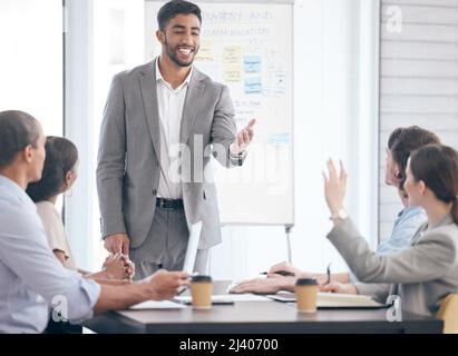 Sei il benvenuto a fare domande. Shot di un gruppo di uomini d'affari in una riunione sul lavoro. Foto Stock