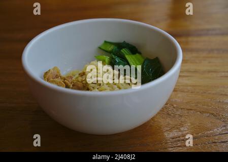 Spaghetti di pollo con verdure verdi in ciotola bianca su tavola di legno Foto Stock