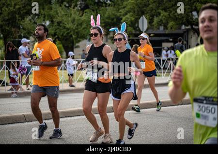 Austin, Texas, Stati Uniti. 10 aprile 2022. I corridori in abito elegante battono verso il traguardo. Oltre 15.000 persone hanno partecipato al Campidoglio 10.000, un 10K gestito dal quotidiano locale, l'uomo di stato americano di Austin. I primi finitori della Cap10K hanno attraversato la linea in poco più di 30 minuti. Credit: Sidney Bruere/Alamy Live News Foto Stock