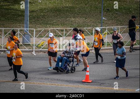 Austin, Texas, Stati Uniti. 10 aprile 2022. Un partecipante corre il Cap 10K mentre spinge un uomo anziano su una sedia a rotelle. Oltre 15.000 persone hanno partecipato al Campidoglio 10.000, un 10K gestito dal quotidiano locale, l'uomo di stato americano di Austin. I primi finitori della Cap10K hanno attraversato la linea in poco più di 30 minuti. Credit: Sidney Bruere/Alamy Live News Foto Stock