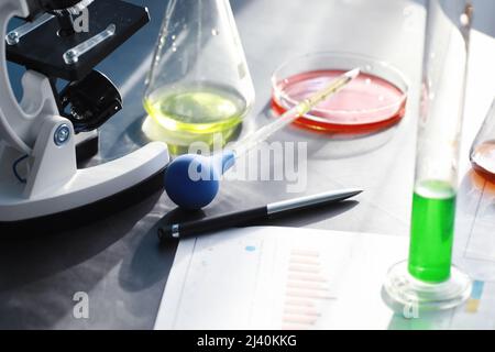 Ricerca di laboratorio. Analisi dei farmaci. Esperimenti chimici in laboratorio. Microscopio varie provette e becher sul tavolo presso il medico ufficiale. Foto Stock