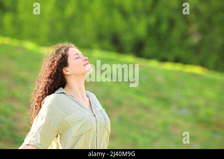 La donna rilassata respira aria fresca in un prato verde in estate Foto Stock