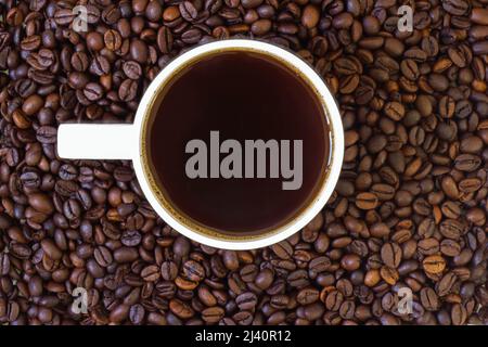 Caffè macinato in grani e caffè caldo appena fatto nella tazza Foto Stock