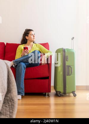 Giovane donna turistica con il suo smartphone in una camera d'albergo Foto Stock