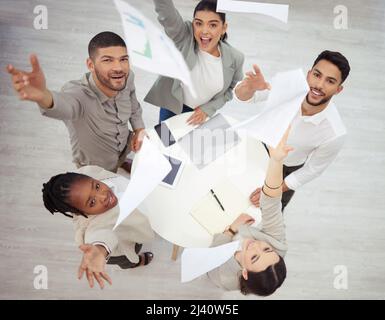 Il valore del successo risiede nel raggiungimento. Scatto aereo di un gruppo diversificato di uomini d'affari che gettano i documenti in aria in festa mentre dentro Foto Stock