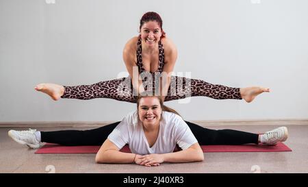 Donna caucasica che fa un cavalletto sulla sua amica. Acrobazie di coppia. Foto Stock