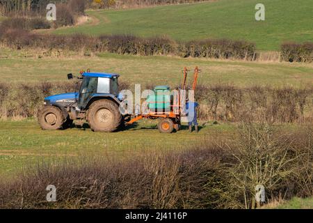 Irvine, Scotland, UK - 25 marzo 2022: Belle terre coloniche scozzesi con campi agricoli e un trattore e agricoltore New Holland ottenere i bracci irroranti re Foto Stock
