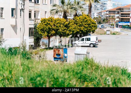 Vecchia spazzatura arrugginita in piedi vicino edificio residenziale in una città del sud. La foto del sito residenziale bidoni spazzatura in piedi sul parcheggio con Foto Stock