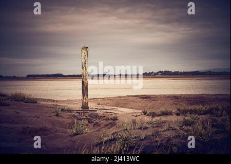 Resti di vecchio molo di legno sull'estuario del fiume Foto Stock