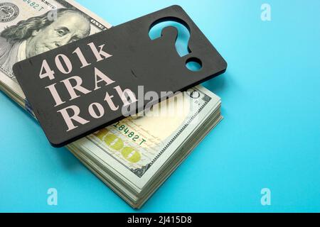 Pila di contanti e piatto con le parole 401k, IRA e Roth piani di pensionamento. Foto Stock