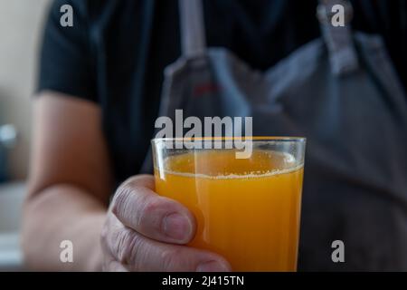 Una persona che tiene un bicchiere di succo d'arancia appena spremuto. Foto Stock