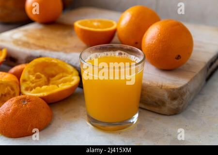 Un bicchiere di succo d'arancia appena spremuto in casa sul piano di lavoro. Foto Stock