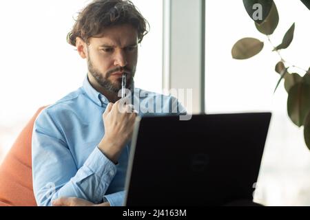 Uomo d'affari concentrato che utilizza il laptop in ufficio Foto Stock