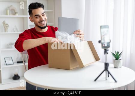 Bel Parcel Blogger maschio arabo Unboxing con laptop sulla macchina fotografica Foto Stock