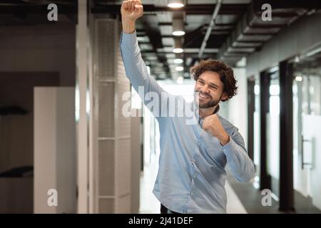 Un uomo d'affari entusiasta che festeggia il successo scuotendo i pugni che urlano sì Foto Stock