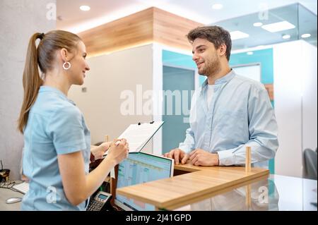 Uomo che parla con un receptionist professionista in clinica Foto Stock