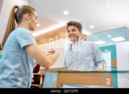 Uomo che parla con un receptionist professionista in clinica Foto Stock