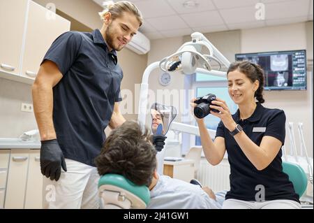 Dentista che fotografa i denti del paziente dopo il trattamento Foto Stock