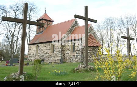 08 aprile 2022, Sassonia-Anhalt, Trüben: Grandi croci in legno si trovano di fronte alla chiesa romanica di Pasqua dal 1170. La Chiesa pasquale fa parte di altre tre chiese a tema del Vorflämig, una Chiesa di Natale, una Chiesa di Inno e una Chiesa biblica, ed è destinata a portare nuovi visitatori nei vecchi luoghi di culto inutilizzati. La Chiesa della comunione è progettata come oggetto d'arte e mostra, tra l'altro, un quadro di comunione con Gesù in un ex mortuario, il suo luogo di sepoltura, un'installazione che mostra l'ingresso di Gesù in Gerusalemme e una grande croce di legno, che è destinata a simboleggiare il crucif Foto Stock