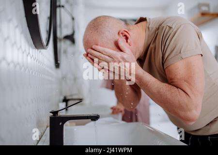 Coppia anziana in bagno, viso di lavaggio, concetto di routine del mattino. Foto Stock