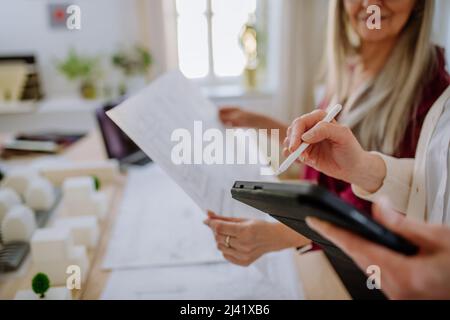 Donne mature eco architetti con progetti che lavorano su tablet insieme in ufficio. Foto Stock