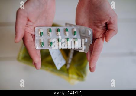 Le mani della donna tengono e gettano pillole scadute al cestino. Foto Stock