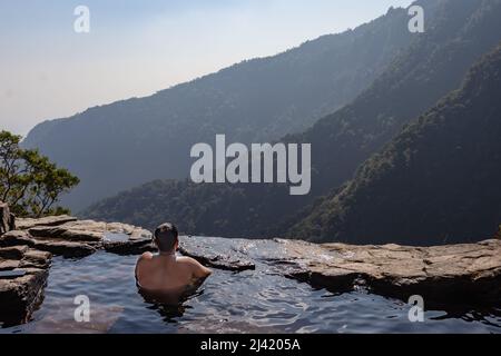 uomo che gode la vista incontaminata presso la piscina naturale sulla scogliera di montagna dall'immagine degli angoli superiori presa a nongnah meghalaya india. Foto Stock