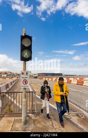 GIBILTERRA, GRAN BRETAGNA - APRILE 9 2022: Turisti che attraversano la pista dell'aeroporto di Gibilterra mentre il semaforo pedonale è verde. Foto Stock