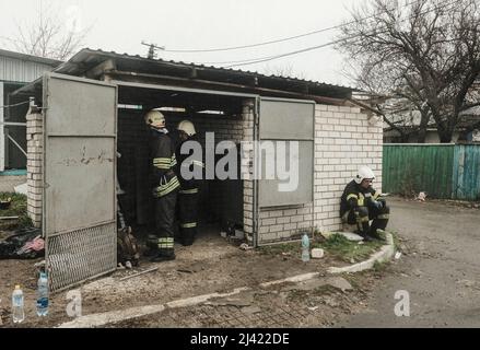 I soccorritori prendono una pausa dalla rimozione delle macerie da un edificio di appartamenti colpito da uno sciopero aereo russo nel villaggio di Borodyanka alla periferia di Kyiv. Durante l'accerchiamento russo di Kyiv molti villaggi e sobborghi fuori della città vide feroci combattimenti e brutale occupazione da parte dei russi invasori che hanno causato numerose vittime civili e denunciato crimini di guerra in tutta la regione. Borodyanska, un villaggio di circa 30 miglia fuori da Kiev, ha visto gli attacchi aerei che hanno sepolto un numero sconosciuto di residenti nel seminterrato dei loro edifici di appartamenti. Foto Stock