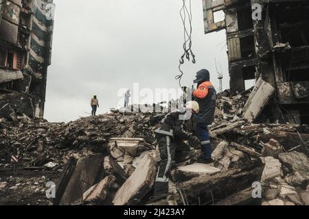 I soccorritori continuano a scavare e rimuovere i detriti da un blocco di appartamenti distrutto che, a quanto pare, seppellì un numero indefinito di civili sotto le macerie. Durante l'accerchiamento russo di Kyiv molti villaggi e sobborghi fuori della città vide feroci combattimenti e brutale occupazione da parte dei russi invasori che hanno causato numerose vittime civili e denunciato crimini di guerra in tutta la regione. Borodyanska, un villaggio di circa 30 miglia fuori da Kiev, ha visto gli attacchi aerei che hanno sepolto un numero sconosciuto di residenti nel seminterrato dei loro edifici di appartamenti. (Foto di Matthew Hatcher Foto Stock