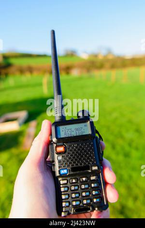 La persona possiede un ricetrasmettitore radioamatoriale Baofeng UV-5R. Foto Stock