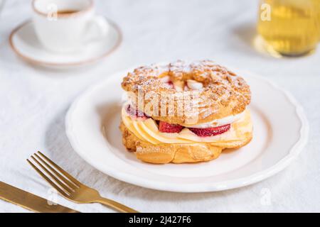 Dessert francese tradizionale chiamato Paris Brest su uno sfondo grigio chiaro con zucchero in polvere e fragole Foto Stock