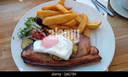 LYTHAM. LANCASHIRE. INGHILTERRA. 11-14-21. Un pasto di gammon, uova fritte e ananas servito con patatine fritte e una guarnitura di insalata. Foto Stock