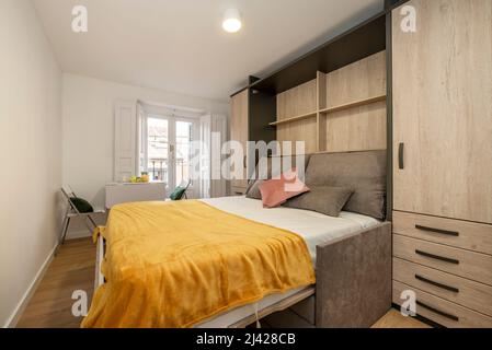 Camera da letto con letto matrimoniale e divano-letto pieghevole, armadio a  muro in legno e pavimento in quercia Foto stock - Alamy