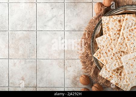 Concetto di festa di Pasqua. Matzah, noce kosher rosso. Tradizionale pane ebraico rituale su sfondo vecchio tavolo di tegole grigio. Cibo di Pasqua. Foto Stock