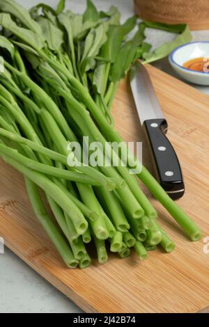 Spinaci freschi di acqua verde cruda, kangkong, su un tagliere di legno primo piano Foto Stock