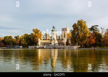 Monumento di Alfonso XII con statua di bronzo sul lago di navigazione, Parque del Retiro (Parco del Retiro), Madrid, Spagna con il colore autunnale in alberi Foto Stock